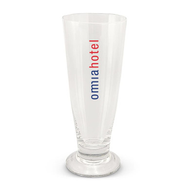 A clear beer glass with a tall, slender design and a base, featuring a logo in red and blue.