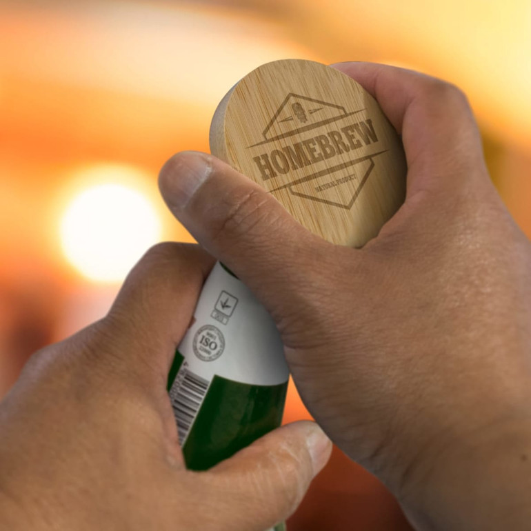 A bamboo bottle opener held in a hand, featuring a circular design and engraved text. The background is softly blurred.