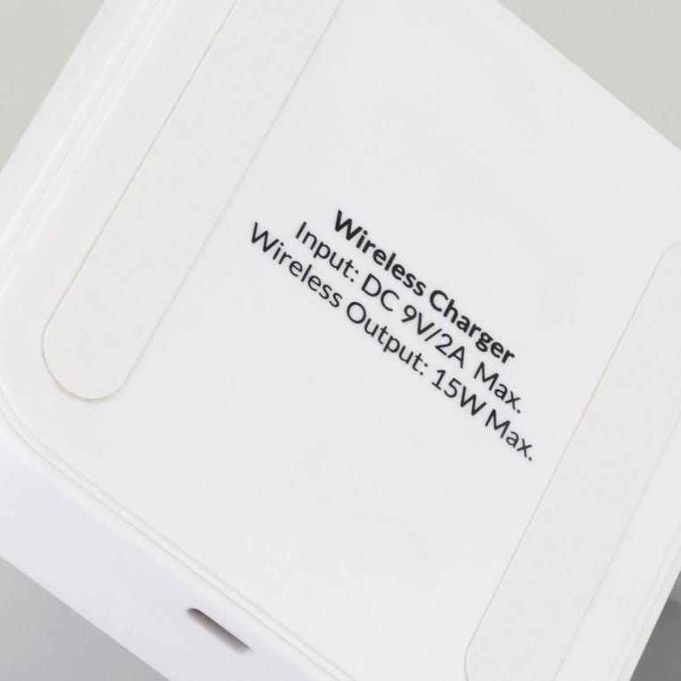 A wireless charging stand in white with a smooth surface and a branding logo on the base.