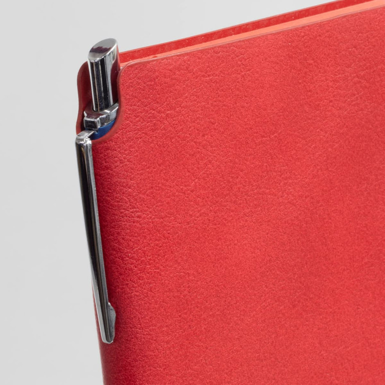 A red notebook with a shiny pen attached to the side. The notebook has a sleek, smooth cover.