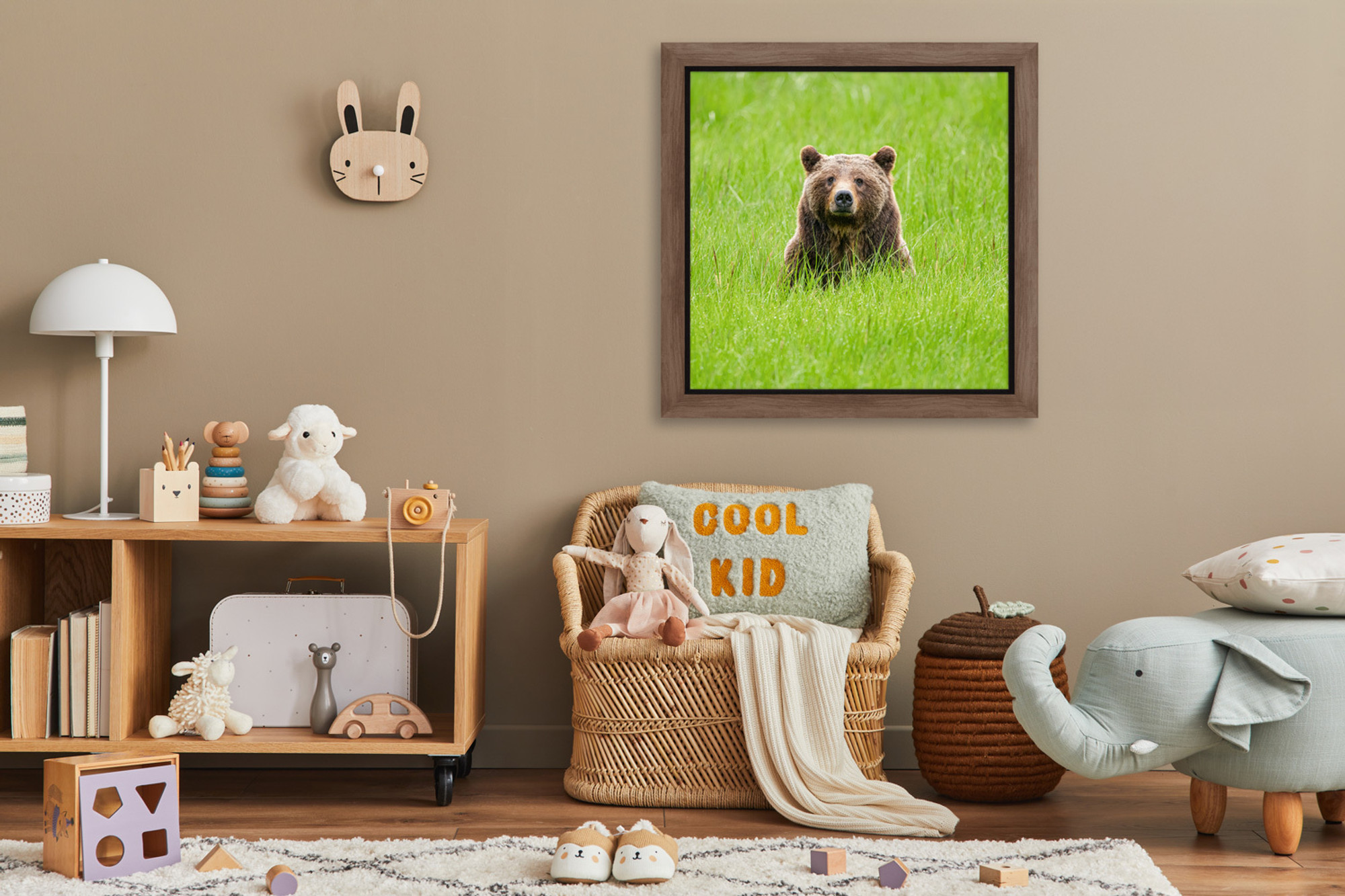Framed fine art print of “One Special Bear” hanging above a child’s bed or play space, portraying Grizzly 399 in a lush spring meadow, her expression soft and calm—an image of quiet strength and maternal grace that comforts and inspires a new generation through conservation photography.