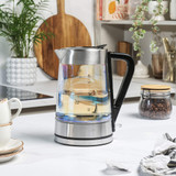 Glass electric kettle with stainless steel and black handle, shown on kitchen worktop.