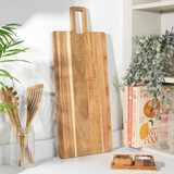 Rectangular wooden chopping board with handle, leaning upright on a kitchen countertop