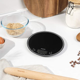 Black digital kitchen scale on countertop with baking ingredients