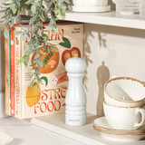 White Salter pepper mill on shelf beside stacked cups and cookbooks