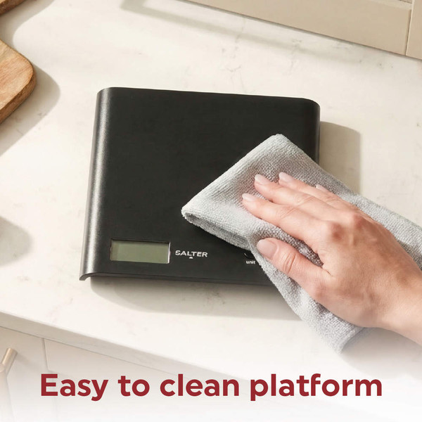 Black digital kitchen scale being wiped clean