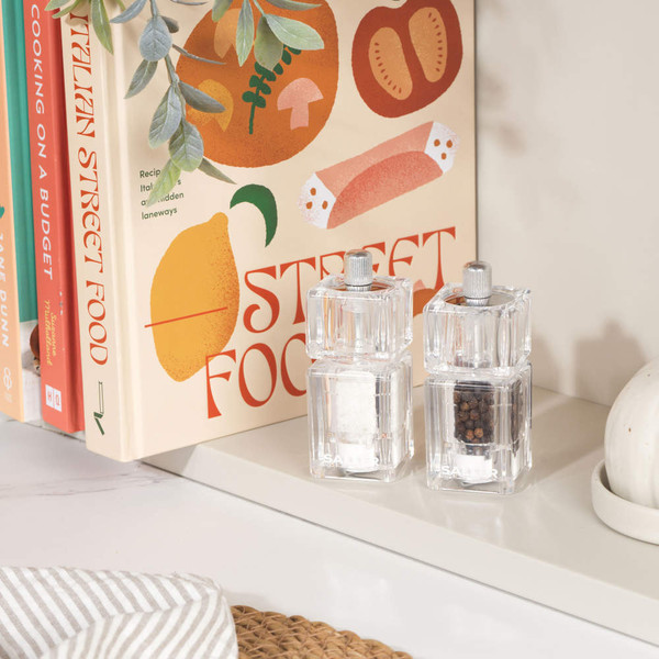 Clear acrylic salt and pepper mills on kitchen shelf