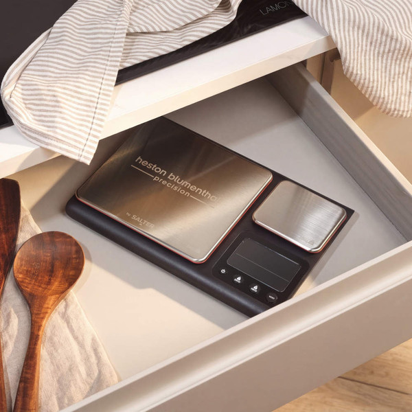 Digital kitchen scale weighing a bowl with baking ingredients, hand pressing zero button