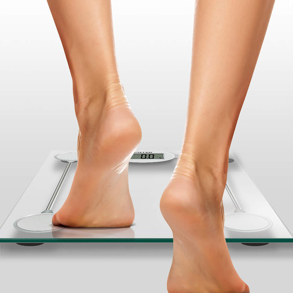 Person stepping onto glass digital bathroom scale