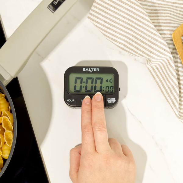 Black Salter digital kitchen timer with three buttons, shown on a fridge door