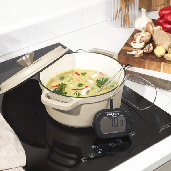 Digital meat thermometer showing 63°C for beef, next to sliced roast beef on chopping board