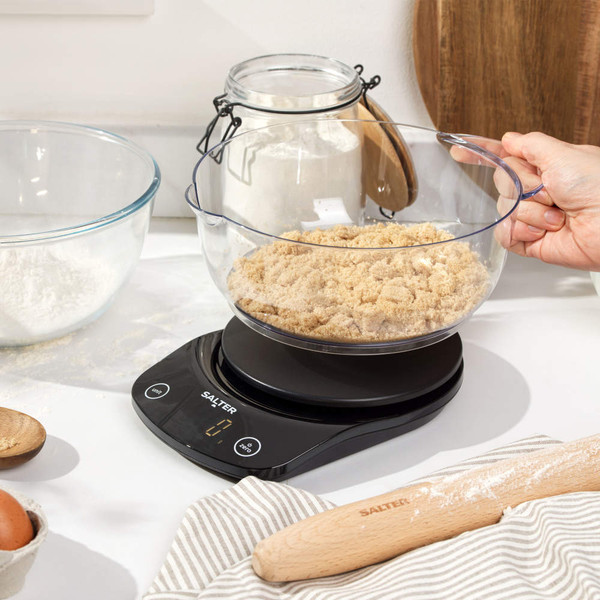 Black digital kitchen scale with large clear bowl on worktop, display shows zero