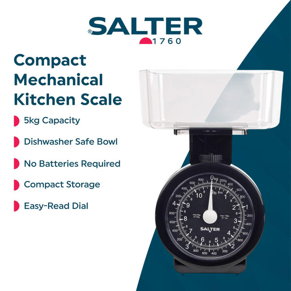 Black mechanical kitchen scale weighing flour, with glass bowl and baking items on counter