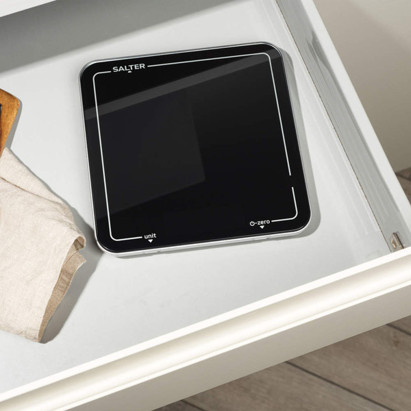 Black digital kitchen scale with touch buttons, shown on a white worktop.