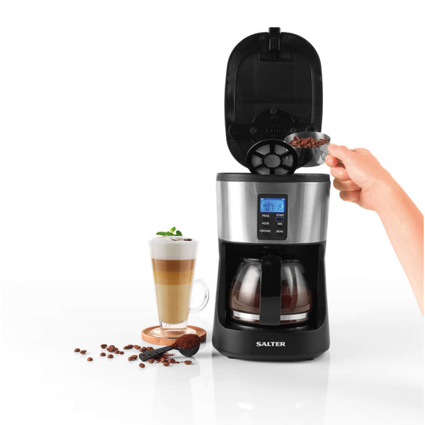 Salter coffee maker in black and silver, lid open, adding beans, glass mug of layered coffee beside.