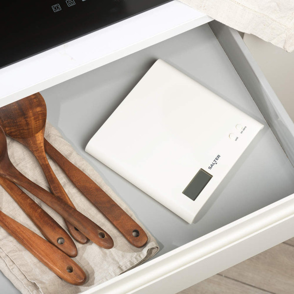 Digital kitchen scale with glass bowl of brown sugar, flour, and rolling pin on worktop