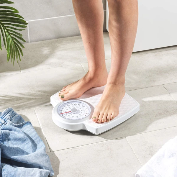 White mechanical bathroom scale close-up, textured surface, shown on tiled floor