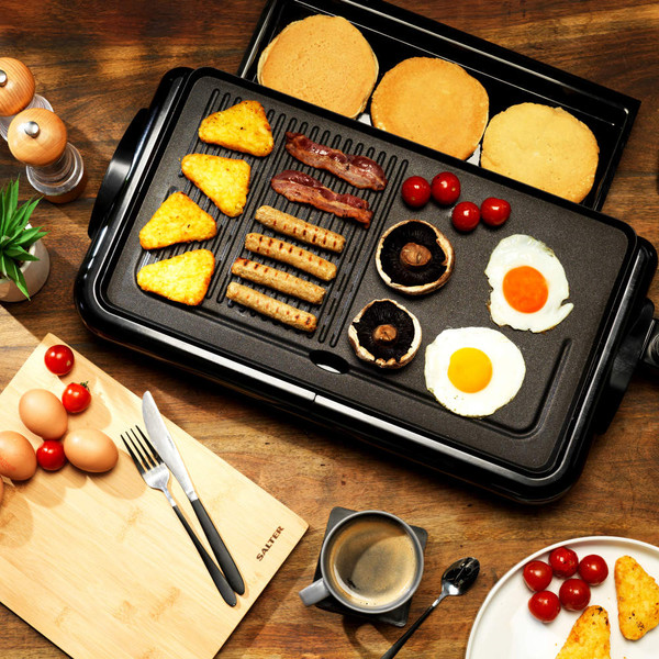 Electric grill with cooked breakfast: eggs, hash browns, sausages, bacon, mushrooms, tomatoes, pancakes.