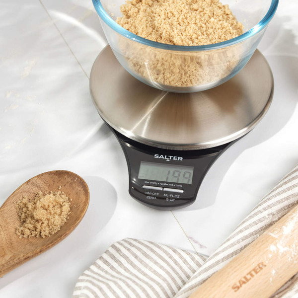 Digital kitchen scale with glass bowl of brown sugar, close-up for baking prep