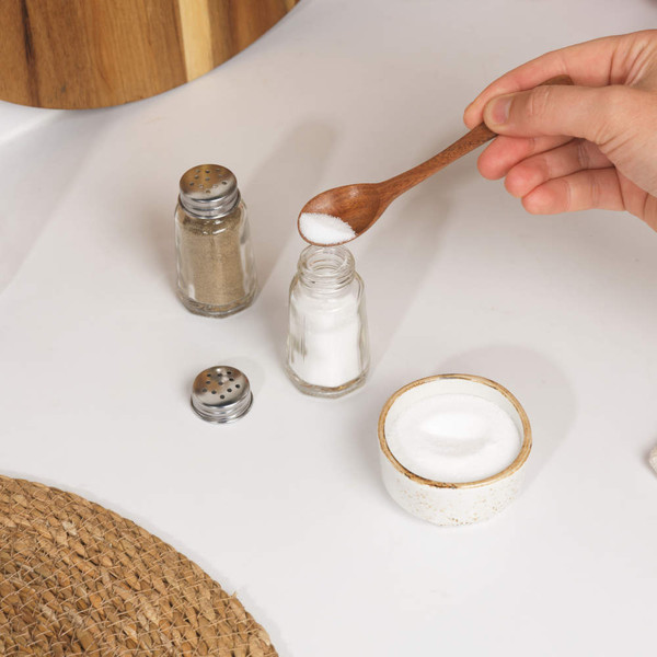 Set of two glass shakers: one filled with salt, one with ground black pepper.