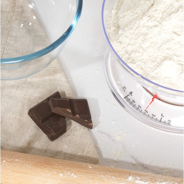 Baking scene with flour on kitchen scale and pieces of dark chocolate on cloth