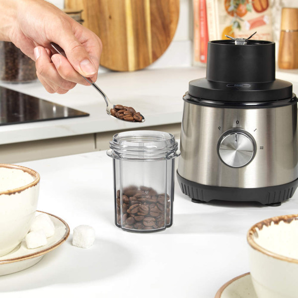 Silver blender with jug filled with fresh fruit, travel bottle, and assorted fruit beside