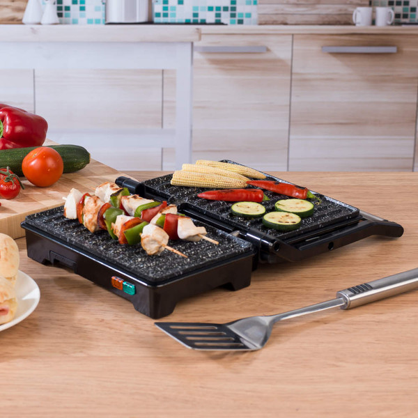 Electric tabletop grill with skewers, vegetables and corn, shown open on a kitchen surface