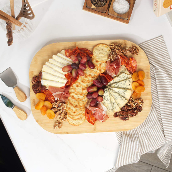 Cheese board with assorted cheeses, crackers, dried fruit, nuts, grapes and cured meats.