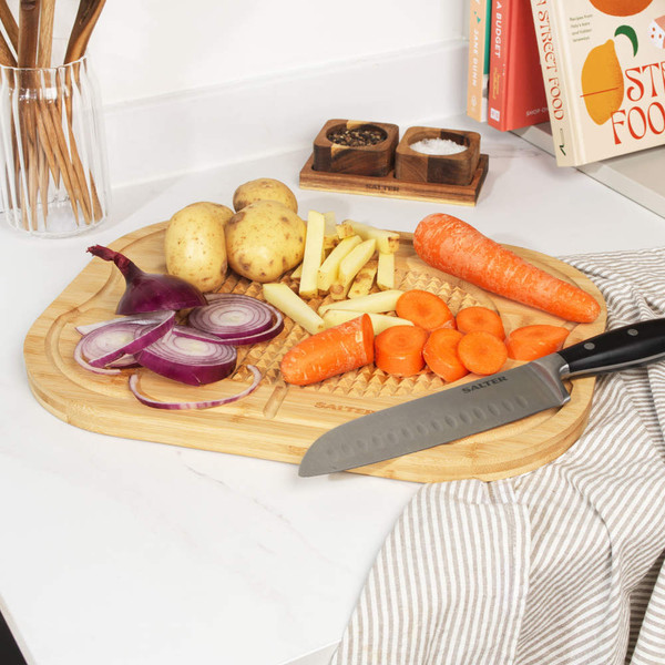 Chopping board with sliced red onion, potatoes, carrots and Salter chef’s knife