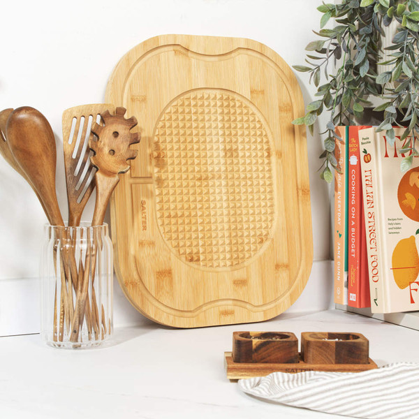 Bamboo chopping board with textured surface, shown on kitchen worktop with utensils.