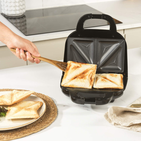 Black sandwich toaster with four toasted sandwich triangles on kitchen worktop