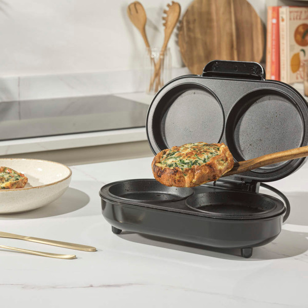 Black Salter snack maker with stainless steel lid and indicator lights, angled view