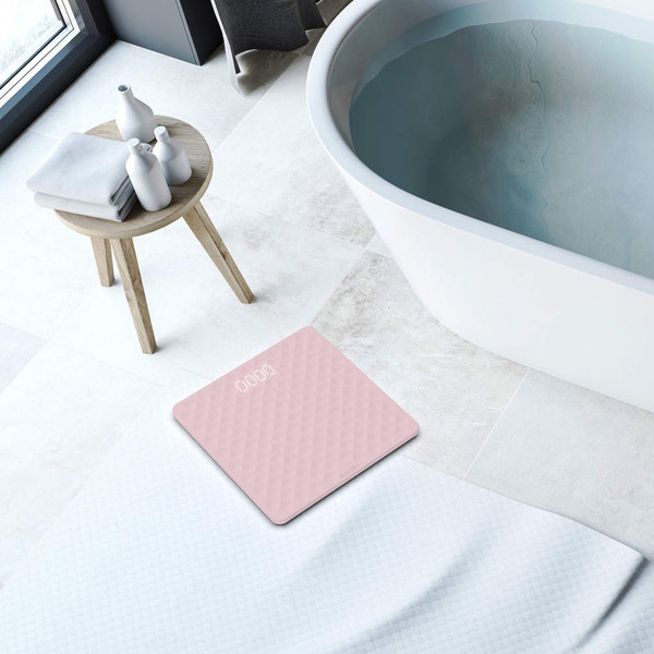 Pink digital bathroom scale on tiled floor beside bathtub
