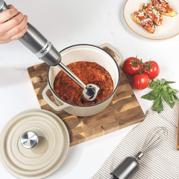 Salter gunmetal hand blender blending tomato sauce in cream casserole dish on wooden board