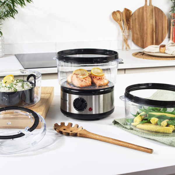 Electric food steamer with three clear tiers and silver base stored in kitchen cupboard