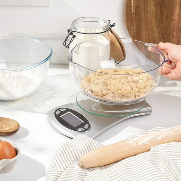 Digital kitchen scale weighing bowl of brown sugar for baking, shown on a countertop