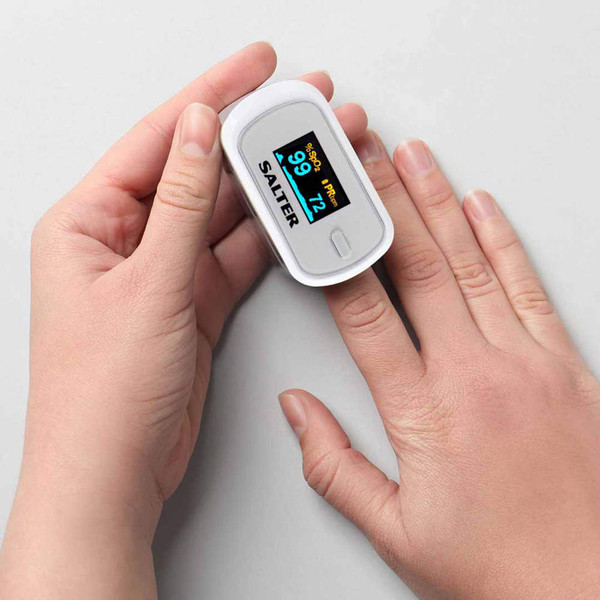 White fingertip pulse oximeter on hand, displaying oxygen and pulse readings