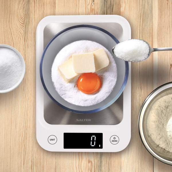 Digital kitchen scale with mixing bowl, egg yolk, butter and sugar for baking