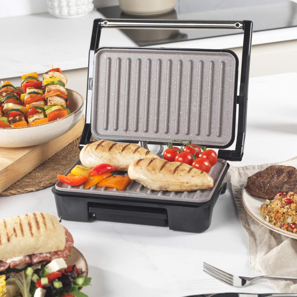 Open electric grill with skewers of grilled chicken and colourful vegetables.