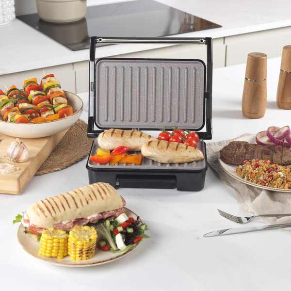 Grey electric grill surface with fat collection tray, close-up showing textured non-stick coating