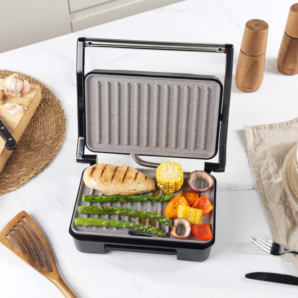 Grey electric grill surface with fat collection tray, close-up showing textured non-stick coating