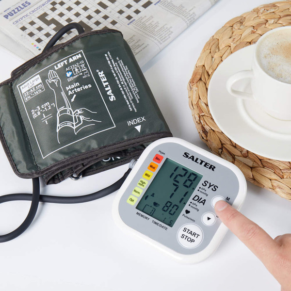 Salter automatic blood pressure monitor with arm cuff, shown in use on a table.