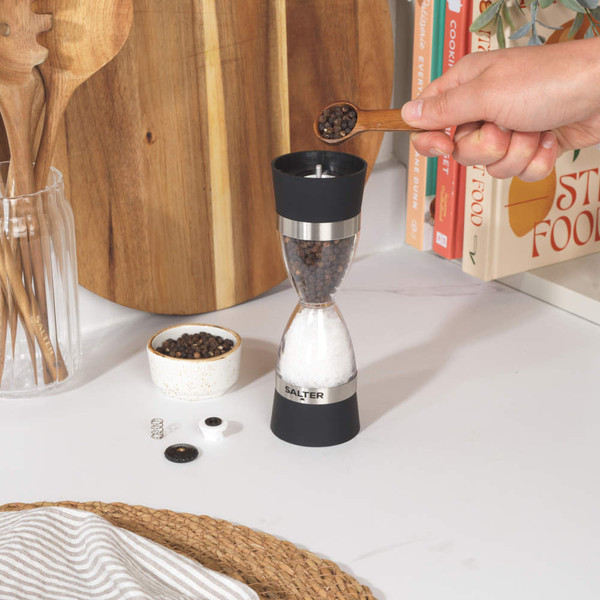 Dual salt and pepper grinder with black and stainless steel finish, shown on kitchen counter.