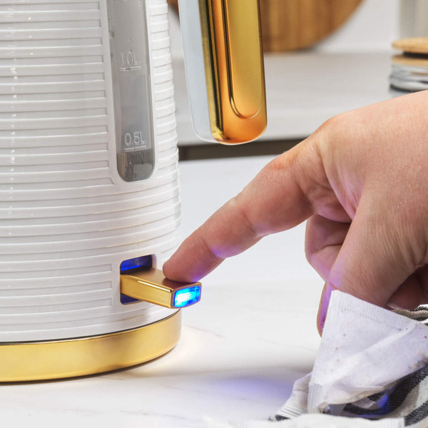 White and gold electric kettle being switched on, close up of illuminated power button.