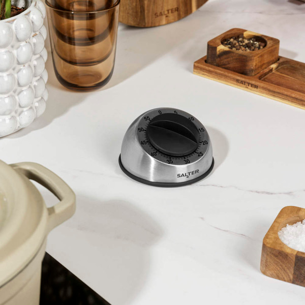 Silver mechanical kitchen timer held in hand, round dial with black knob
