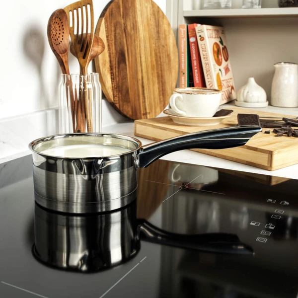 Set of stainless steel saucepans and frying pan on kitchen counter, food shown inside