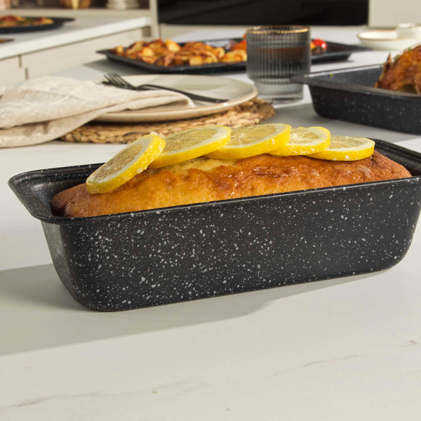Grey speckled loaf tin with lemon drizzle cake on kitchen worktop