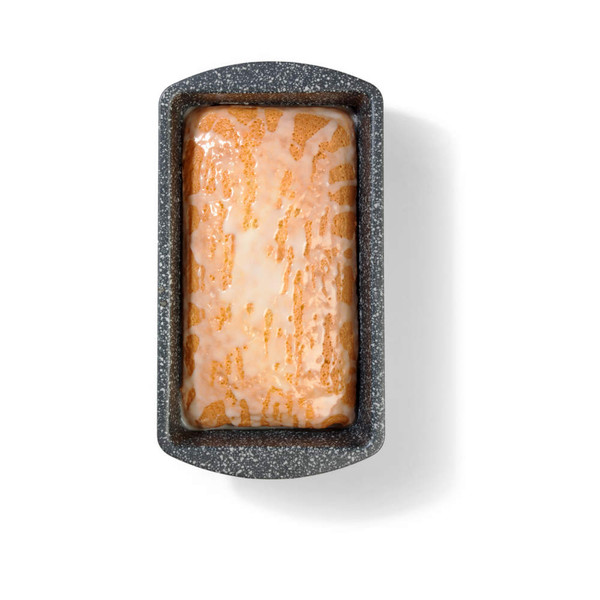 Iced loaf cake in a speckled grey tin, shown from above.