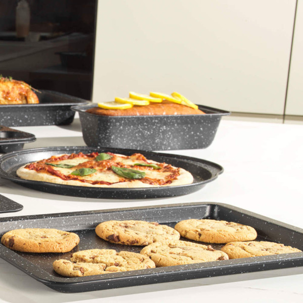Black speckled baking tray with chocolate chip cookies on kitchen worktop
