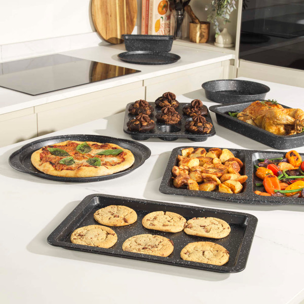 Set of grey speckled non-stick baking trays on kitchen counter with cooked food